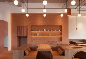 A modern restaurant interior with terracotta walls and wooden seating and fixtures.