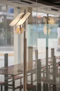 A modern metallic standing lamp with adjustable panels in an interior setting.