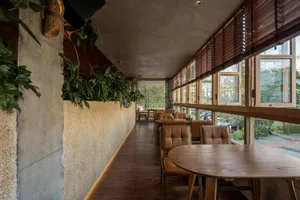 Industrial-style restaurant interior with wooden furniture and greenery.