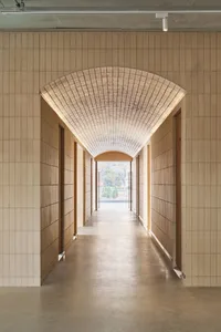 A minimalist corridor with tiled walls and an archway overhead.