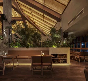 A modern restaurant interior featuring wood, concrete, and plaster materials.