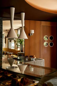 A modern interior design of a restaurant bar with a wooden counter, marble surface, and concrete and wooden elements.