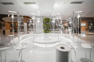 Modern shopping center lobby featuring glass partitions, concrete columns, and LED lighting.