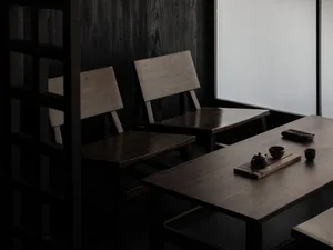 Two wooden tables and chairs in a dimly lit restaurant setting.