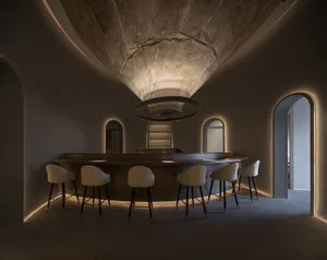 A modern restaurant bar counter made of concrete with white chairs.