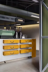 Industrial-style coffee shop counter with wooden drawers and metal fixtures.
