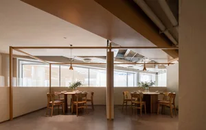 Industrial-style restaurant interior with wooden tables, glass sliding walls, and metal pipes