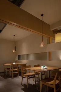 A modern restaurant interior features wooden tables and chairs.
