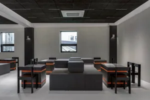 Industrial-style cafe with black wooden tables and chairs, featuring a minimalist design with clean lines and a monochromatic