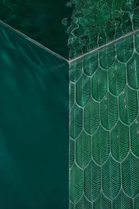 A close-up view of green scallop-patterned glass tiles