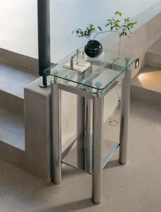 A sleek, modern glass and metal side table with a small plant in a black vase.