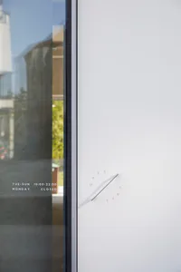 Modern storefront window with hours of operation printed on it.