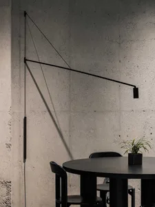 A black dining table and chairs against a concrete wall with a minimalist design.