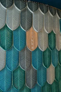 A decorative wall featuring ceramic tiles arranged in a leaf-like pattern with the word 'tikka' inscribed in the center.