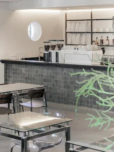A modern coffee shop with concrete walls, tables, and chairs.