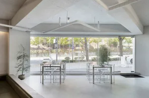 Modern minimalist coffee shop interior design featuring metallic furniture, glass windows, and a leather sofa.