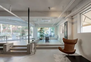 A modern coffee shop featuring a minimalist design with concrete finishes and large windows.