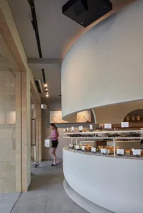 A modern bakery interior featuring concrete, glass, and metal materials.