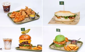 A food tray containing various food items such as fried chicken, waffles, a burger, fries, and an iced coffee drink.