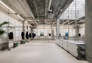 Concrete walls, ceiling, and floor of a retail space with hanging clothing racks.