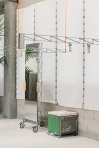 Metal draping stand with green storage box in industrial setting