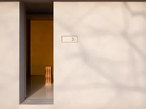 A minimalist doorway featuring concrete material with a yellow door visible inside the doorway.
