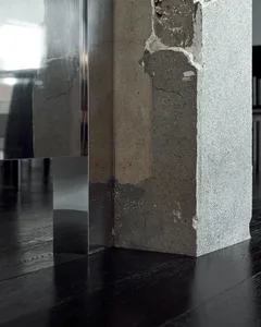Minimalist interior design featuring a concrete column on a dark wooden floor.