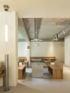 Modern minimalist restaurant interior featuring wooden benches and tables.
