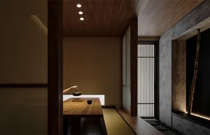 A minimalist tea room with a wooden table and floor, featuring a hand holding a teapot and a cup.