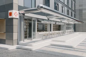 A modern coffee shop exterior featuring glass, metal, and concrete materials.