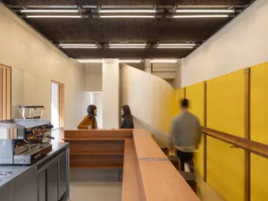 A modern coffee shop interior with yellow walls and a wooden counter.