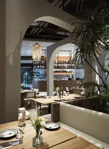Restaurant interior with wooden tables, chairs, and a bar in the background.