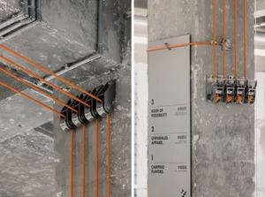 A series of orange cords attached to metal rails on a concrete column, with signage indicating floor levels '1', '2', and '3'