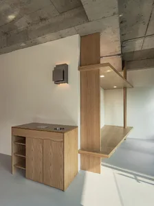 A minimalist kitchen featuring wooden cabinets and shelves, with a sleek, clean design.