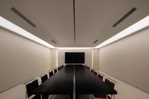 A minimalist conference room featuring a long black table and white walls.