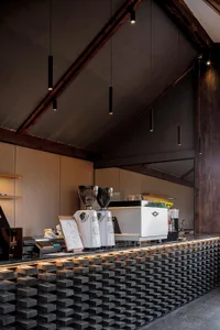 A modern coffee shop counter with metal elements and a brick-like pattern on the floor.