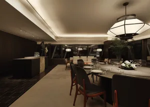 A modern dining room with black leather chairs, a round dining table, and a large pendant light hanging above.