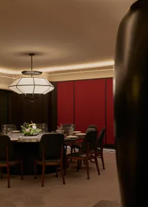 A modern dining room with wooden floors, leather upholstered chairs, and fabric tablecloth.