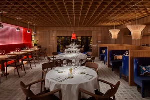 A modern restaurant interior with wooden tables, chairs, and walls.