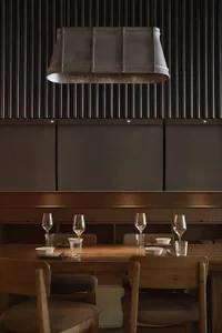 A rustic, industrial-themed restaurant interior with wood furniture, metal accents, and dark, dramatic lighting.
