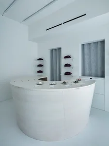 A minimalist retail space with a concrete countertop featuring small plates of food and accessories.