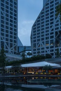 High-rise buildings illuminated at dusk with a glass facade and urban landscape.