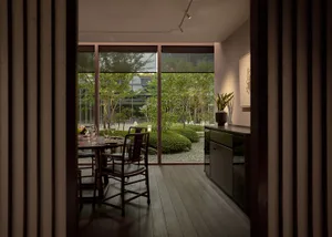 Modern dining room with garden view, featuring wood and glass materials.