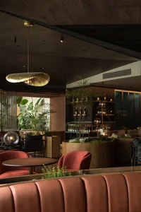 Modern restaurant bar with wood and concrete finishes, featuring elegant seating and a well-stocked bar.