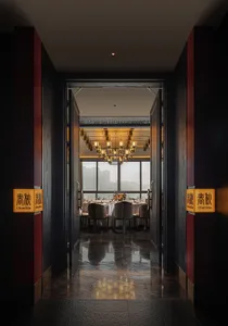 Modern, industrial-themed restaurant interior with marble flooring, large windows overlooking a cityscape, and a warm, inviti