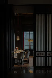 Modern restaurant interior with wooden floors, glass walls, and fabric curtains.