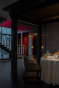 Modern restaurant interior with red walls and marble flooring featuring a dining table set for two.