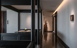 A minimalist dining room with dark wooden tables and chairs, clean lines, and a single flower arrangement on the table.