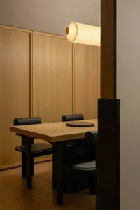 Modern dining room featuring a wooden table with black chairs and a minimalist design.