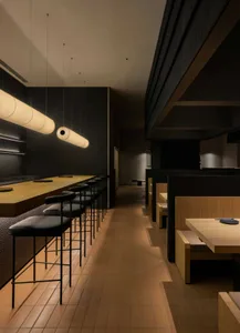 A modern restaurant with black and wooden interiors featuring sleek seating arrangements and contemporary lighting fixtures.